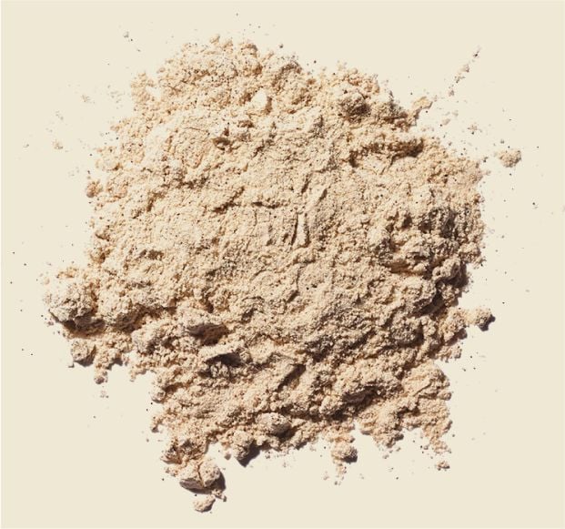 A pile of light brown, finely ground powder scattered on a neutral background.