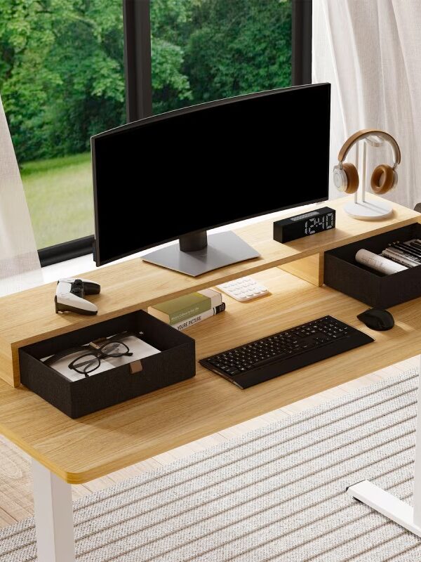 A tidy desk setup with a monitor, keyboard, mouse, desk organizer, books, headphones, and a digital clock. A large window with a view of green trees is in the background.