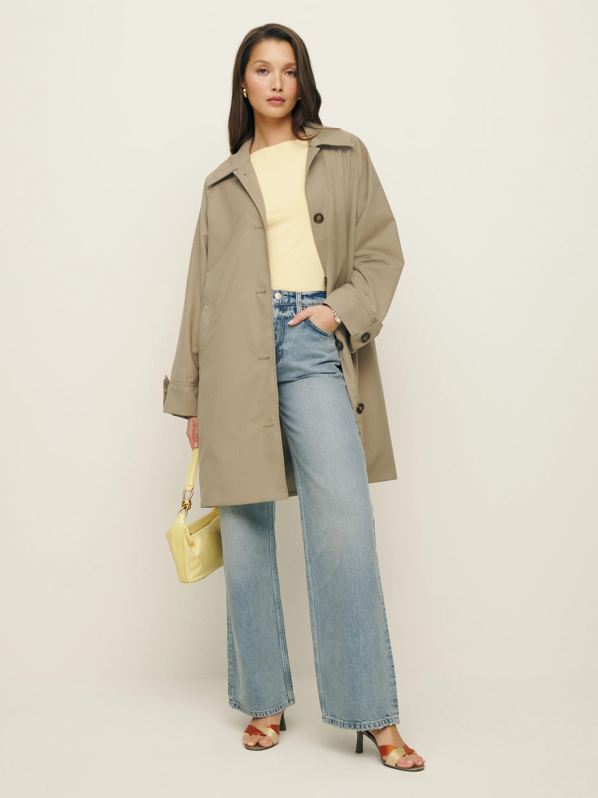 A model wearing a trench coat and wide leg jeans.