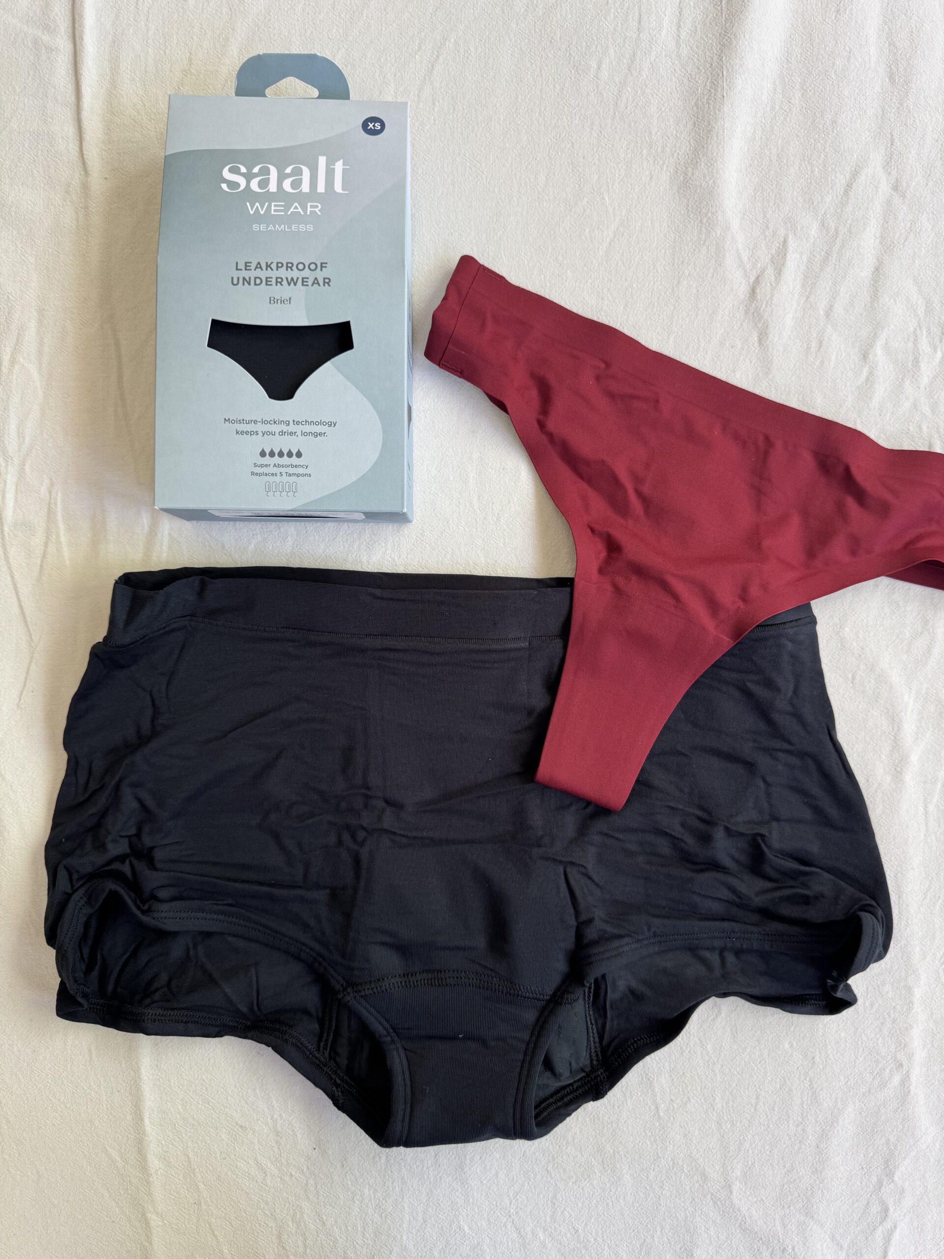 Black and red leakproof underwear set with packaging on a white surface.