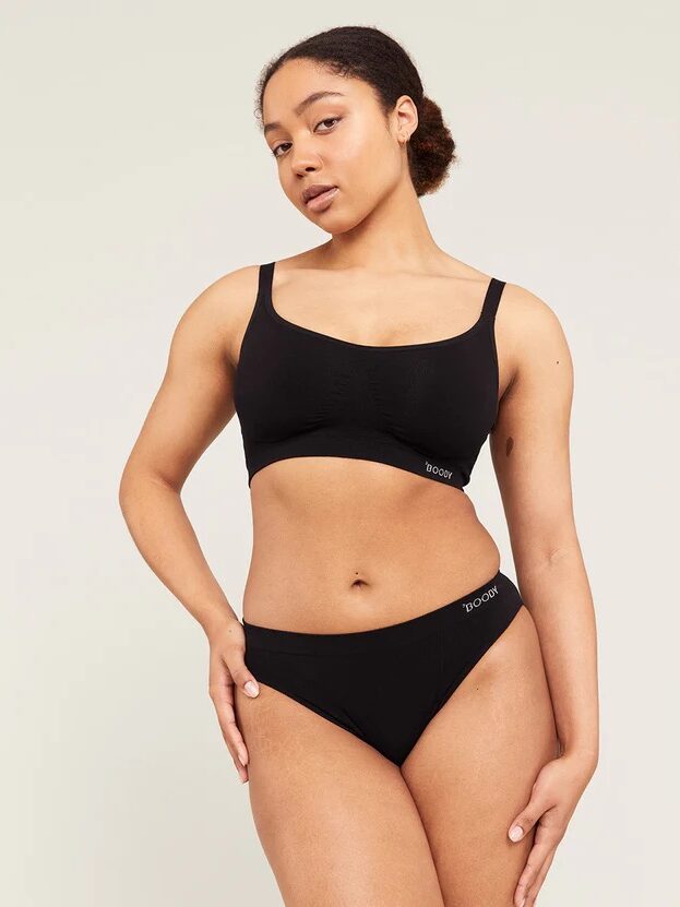 Person wearing a black sports bra and briefs, posing against a neutral background.