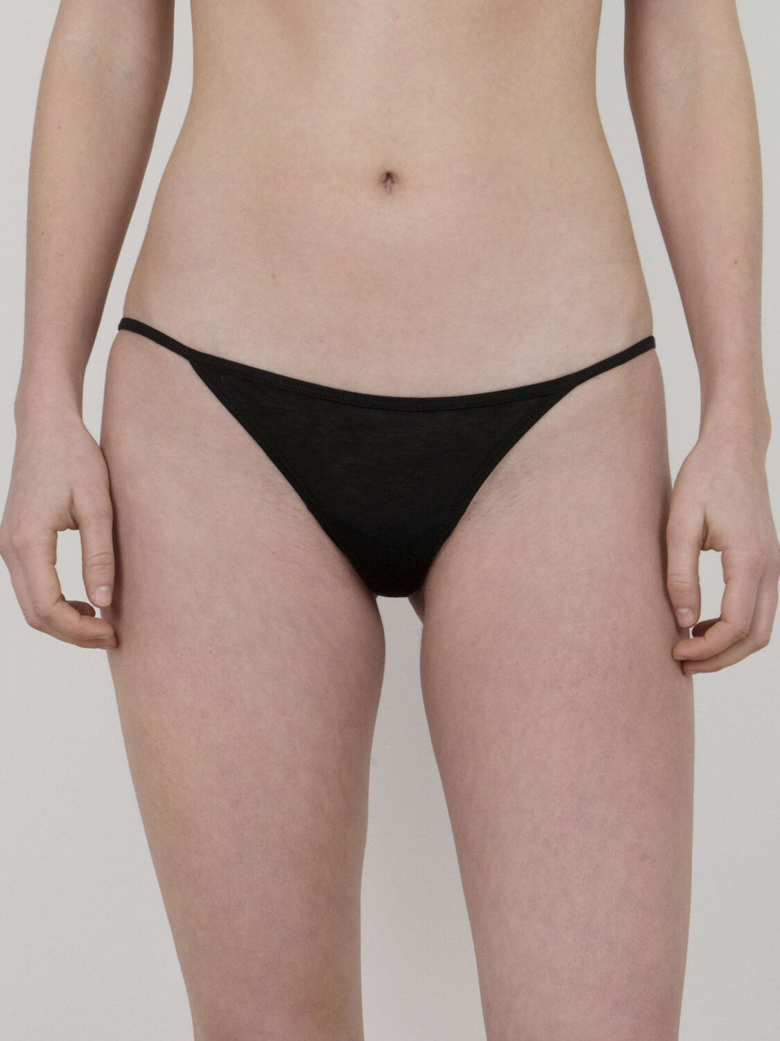 Person wearing black underwear, standing against a plain background.