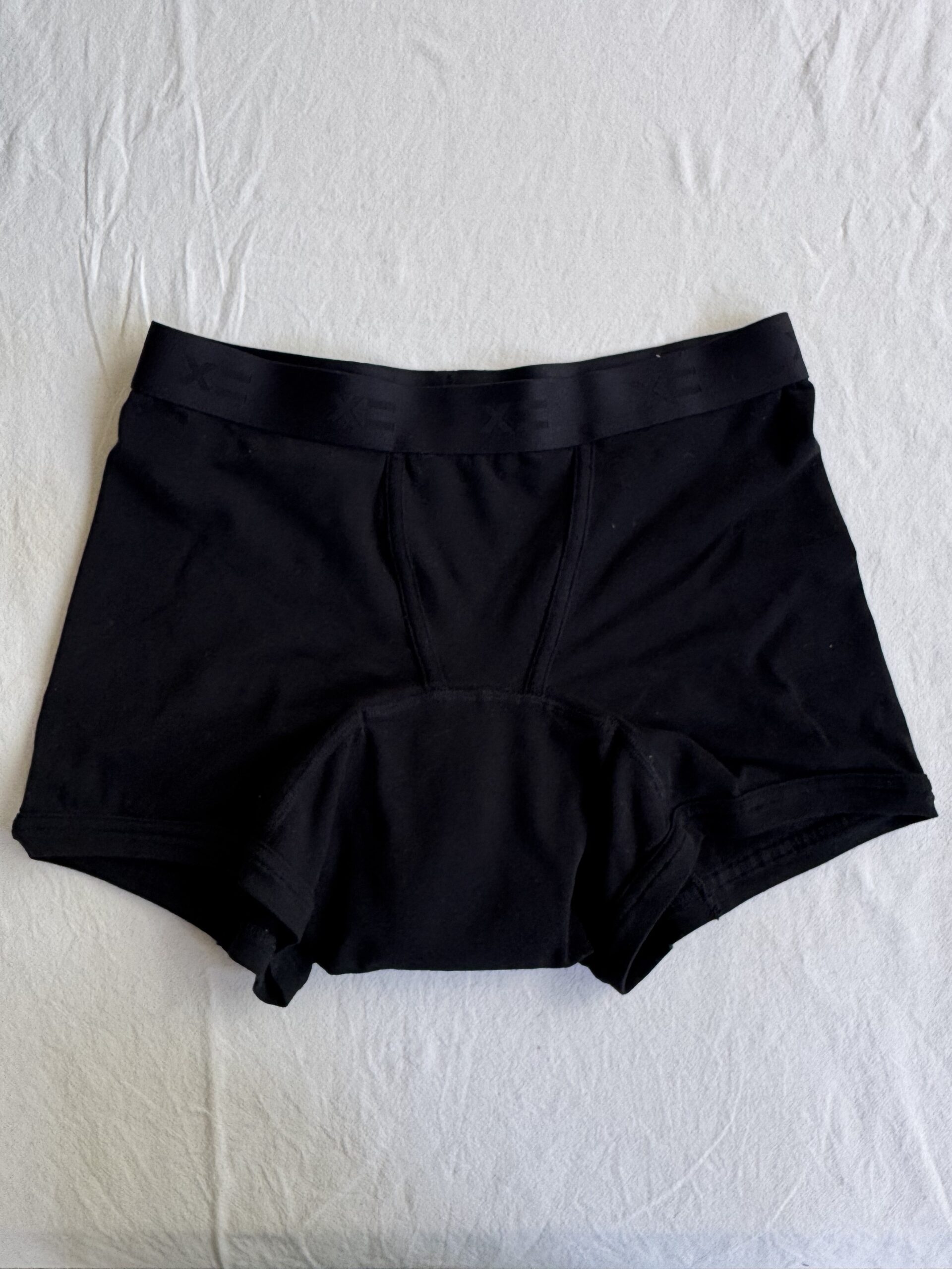Black boxer briefs lying flat on a white surface.