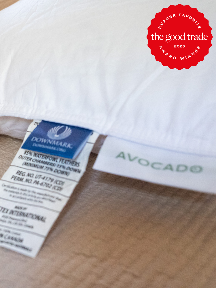 Close-up of a pillow with labels showing materials and brand names "Downmark" and "Avocado". A red badge indicates it as a "Reader Favorite" award winner in 2025 by "The Good Trade".