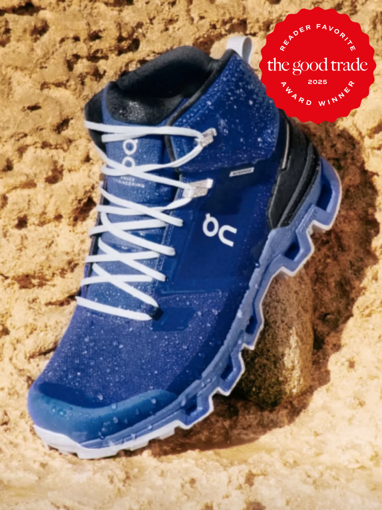 Blue hiking boot with white laces on a rocky surface, featuring the "The Good Trade 2025 Reader Favorite Award Winner" badge.