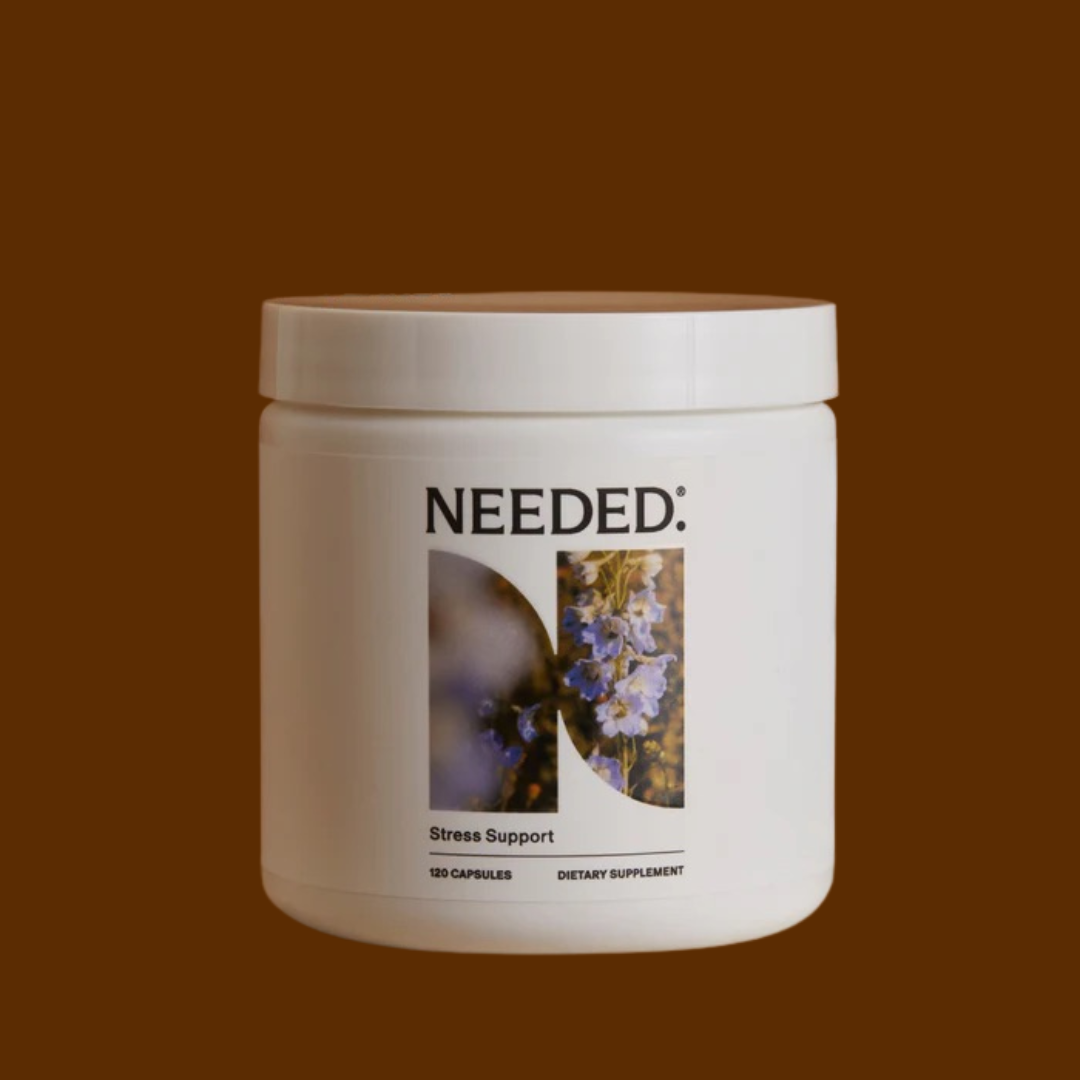 A white container labeled "NEEDED: Stress Support" with an image of purple flowers, containing 120 dietary supplement capsules, set against a solid brown background.