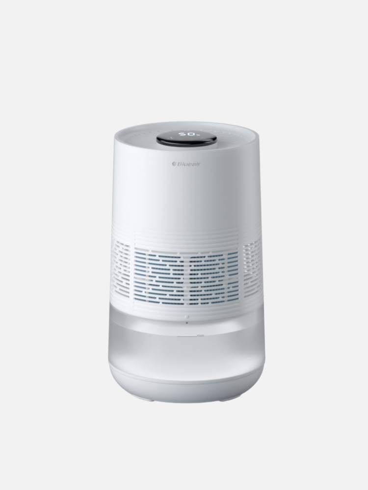 A white, cylindrical air purifier with a digital display on top and vent patterns on the sides, placed against a plain background.
