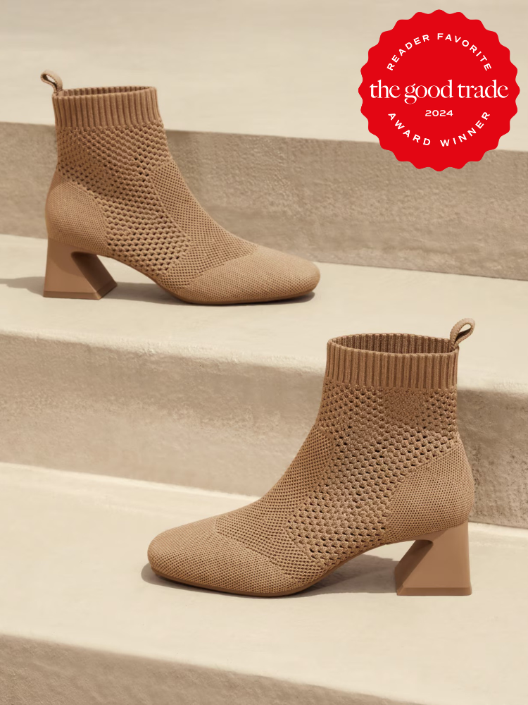 A pair of light brown, knitted ankle boots with block heels displayed on steps. The top right corner features a red "The Good Trade 2024 Reader Favorite Award Winner" badge.