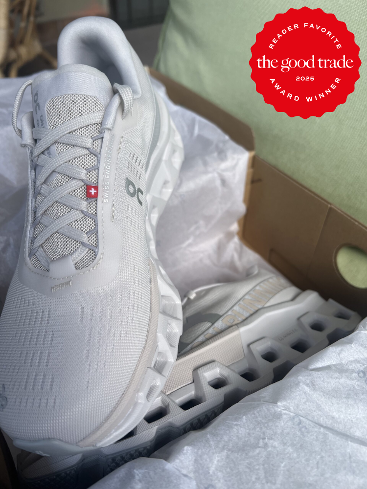 A pair of white athletic shoes in a shoebox, with a red badge stating "The Good Trade - Reader Favorite Award Winner 2023" in the top right corner.