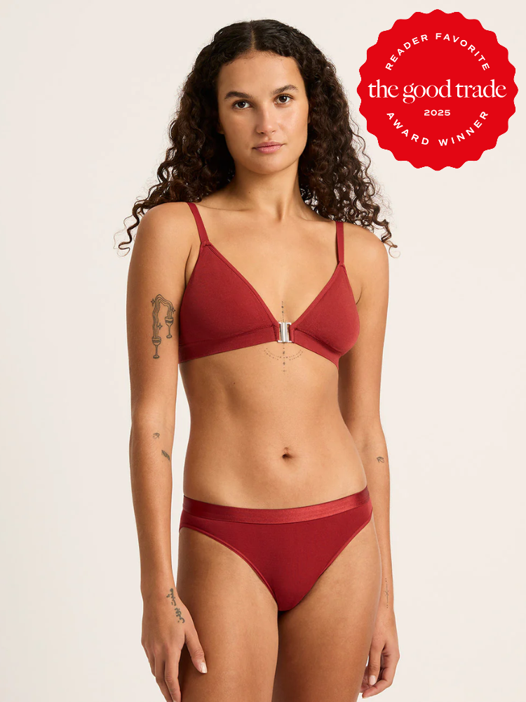 A person wearing a red bikini stands in front of a plain background. There's an award badge in the upper right corner.