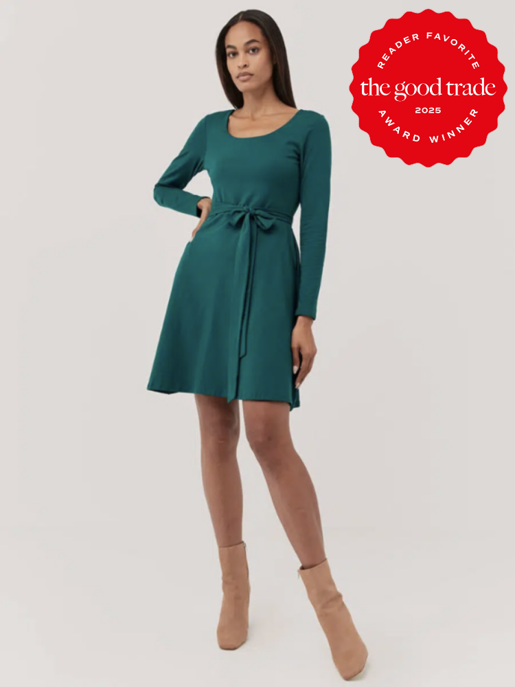 A woman in a teal long-sleeve dress with a tie waist poses against a plain background. She's wearing tan ankle boots. A "The Good Trade 2023 Award Winner" badge is displayed in the top right corner.